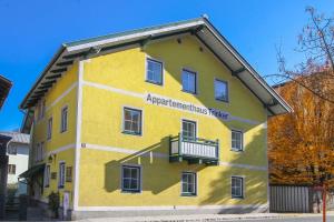 a yellow building with a balcony on the side at Appartements Trinker in Zell am See