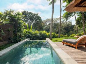 a swimming pool in a backyard with a chaise lounge and a resort at Maya Ubud Resort & Spa in Ubud