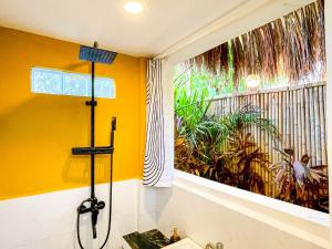 a yellow bathroom with a shower and a window at Cosy Villa & Apartments - Siargao in General Luna