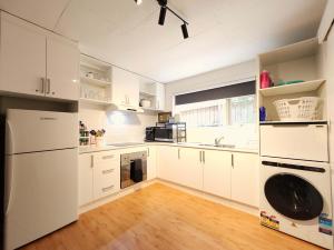 a kitchen with white cabinets and a washer and dryer at Spacious Aloha Suite with Full Kitchen, Southland, Golf Nearby in Highett