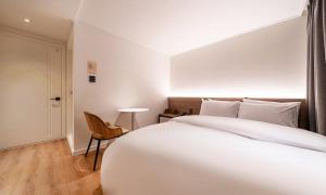 ein Schlafzimmer mit einem großen weißen Bett und einem Stuhl in der Unterkunft 신촌 어반슬로우 in Seoul