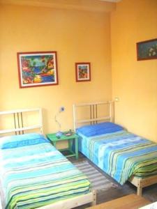 two beds are in a room with yellow walls at La Papaya in Marina di Pisa