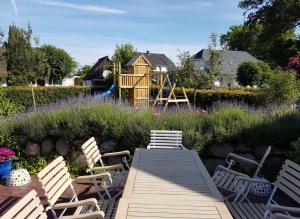 a garden with a wooden table and chairs and a playground at Alte Boddenkate in Born