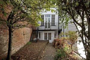 a white house with a balcony and a brick wall at Modern Flat on the seafront Exmouth in Exmouth