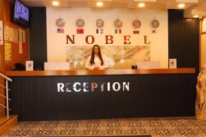 a woman standing behind a counter in a hotel reception at Ephesus Nobel Otel in Selçuk