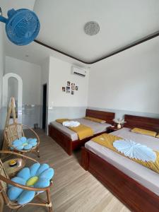 a bedroom with two beds and a chair and a clock at Happy Villa in Phú Hiệp