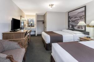 a hotel room with two beds and a flat screen tv at Super 8 by Wyndham Kelowna BC in Kelowna