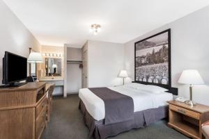 a hotel room with a large bed and a desk at Super 8 by Wyndham Kelowna BC in Kelowna