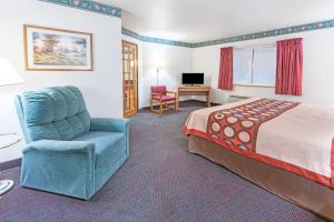 a hotel room with a bed and a chair and a television at Super 8 by Wyndham Richfield Cleveland in Richfield
