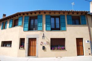 un edificio con ventanas y flores en las cajas de las ventanas en El Capricho de Ana, en Neila de San Miguel