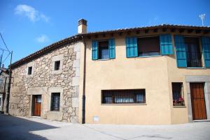 a stone building with blue windows on a street at El Capricho de Ana in Neila de San Miguel