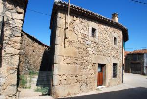 Un antiguo edificio de piedra con una puerta de madera. en El Capricho de Ana, en Neila de San Miguel 54 fotos más