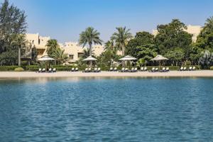 a beach with chairs and umbrellas on the beach at Grand Hyatt Doha Hotel & Villas in Doha
