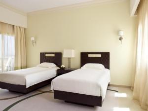 two beds in a room with white walls and windows at Grand Hyatt Doha Hotel & Villas in Doha +121 photos