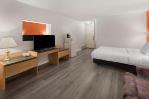 a hotel room with a bed and a desk with a television at Howard Johnson by Wyndham Edson in Edson