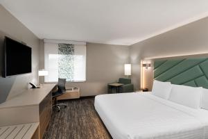 a hotel room with a large bed and a desk at Wingate by Wyndham Jackson in Jackson