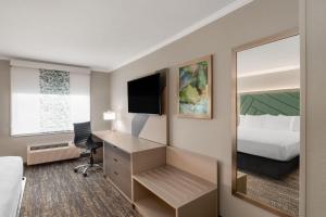 a hotel room with a bed and a desk with a mirror at Wingate by Wyndham Jackson in Jackson