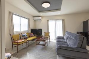 a living room with a couch and chairs at ev itoshima in Itoshima