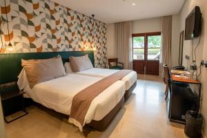 a bedroom with a large bed and a television at Maristel Hotel & Spa - Adults Only in Estellencs