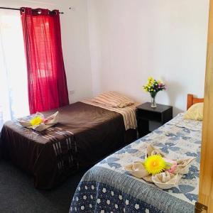 two beds in a room with flowers on them at Hostal y Cabañas Pua Vaenga in Hanga Roa +44 photos