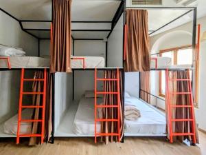 three bunk beds with orange ladders in a room at Scodrinon Hostel in Shkodër +58 photos
