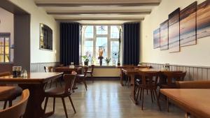 a restaurant with wooden tables and chairs and a window at Hotel Münchner Löwenbräu in Cuxhaven