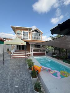 a house with a swimming pool in front of a house at Peace poolvilla sattahip พีซ พลูวิลล่า สัตหีบ in Ban Tao Than