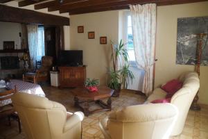 a living room with two white chairs and a tv at Charmante maison à la ferme in Valderiès