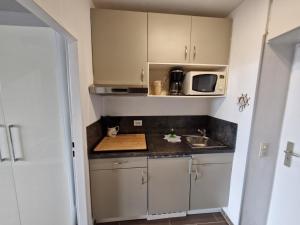 a small kitchen with a sink and a microwave at Die lütte Kajüte Südstrand in Fehmarn