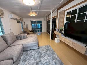 a living room with a couch and a flat screen tv at Peace poolvilla sattahip พีซ พลูวิลล่า สัตหีบ in Ban Tao Than