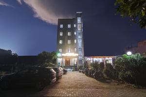 a tall building with cars parked in a parking lot at Status By Hotel The Emporio in Ghaziabad