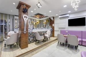 a restaurant with a bar with chairs and a tv at Status By Hotel The Emporio in Ghaziabad