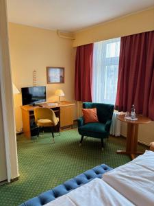 a hotel room with a bed and a desk and chairs at Hotel Waldperle in Göhren