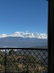 a view of snow covered mountains from a window at Hotel Sumit in Kausani