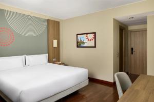 ein Schlafzimmer mit einem Bett, einem Schreibtisch und einem Tisch in der Unterkunft iStay by NH Zaragoza Sport Hotel in Saragossa