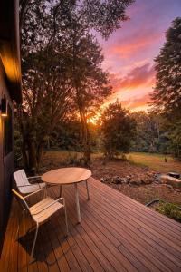 a table and two chairs on a deck with a sunset at The Flower Sanctuary Tiny Home in Springbrook