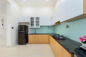 a kitchen with a black refrigerator and wooden cabinets at Villa 5 Lạc Long Quân - Bãi Sau in Vung Tau