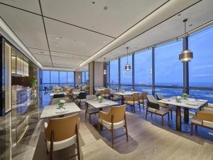 a restaurant with tables and chairs and large windows at Hilton Quzhou in Quzhou