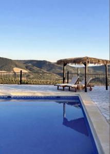 a swimming pool with a straw umbrella and two lounge chairs at Cortijo Sol y Olivo spacious exclusive private pool retreat in Algarinejo +18 photos