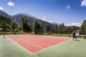 two people playing tennis on a tennis court at Huttopia Val Cenis in Val Cenis
