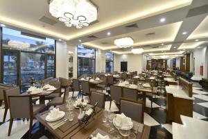 a restaurant with tables and chairs and windows at Garco Dragon Hotel in Hanoi