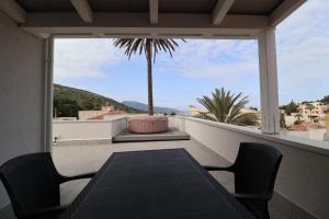 a balcony with a table and chairs and a palm tree at Mastru Cicciu in Custonaci
