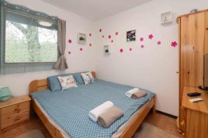 a bedroom with a bed with blue sheets and a window at PART II apartman in Tiszaug