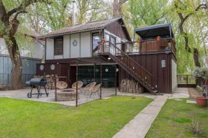 a house with a deck with a grill and chairs at PART II apartman in Tiszaug
