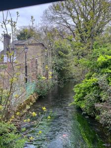 a river next to a brick building and trees at St Marys Cottages 1 in Dover