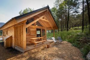 a small wooden cabin with a table and two chairs at Huttopia Val Cenis in Val Cenis
