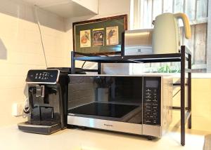 a microwave sitting on a counter next to a coffee maker at Spacious Guest Room 7 Sleeps 5 Near Shops with Free Parking in Highett