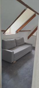 a couch sitting in a room under some stairs at Studio avec vu sur le Loir in La Flèche