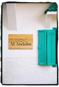 a sign on the side of a wall with green shutters at Dar Al-Andalus in Tamraght Ouzdar