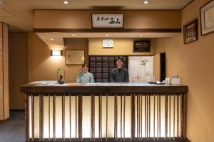 two people standing behind a bar in a restaurant at NISHIYAMA RYOKAN Established in 1953 in Kyoto